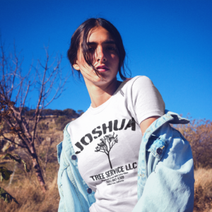 joshua-tree-service-t-shirt-a-woman-on-a-motorcycle-in-the-desert-the-secret-tours-joshua-tree-national-park-adventure-camping-climbing-hiking-white